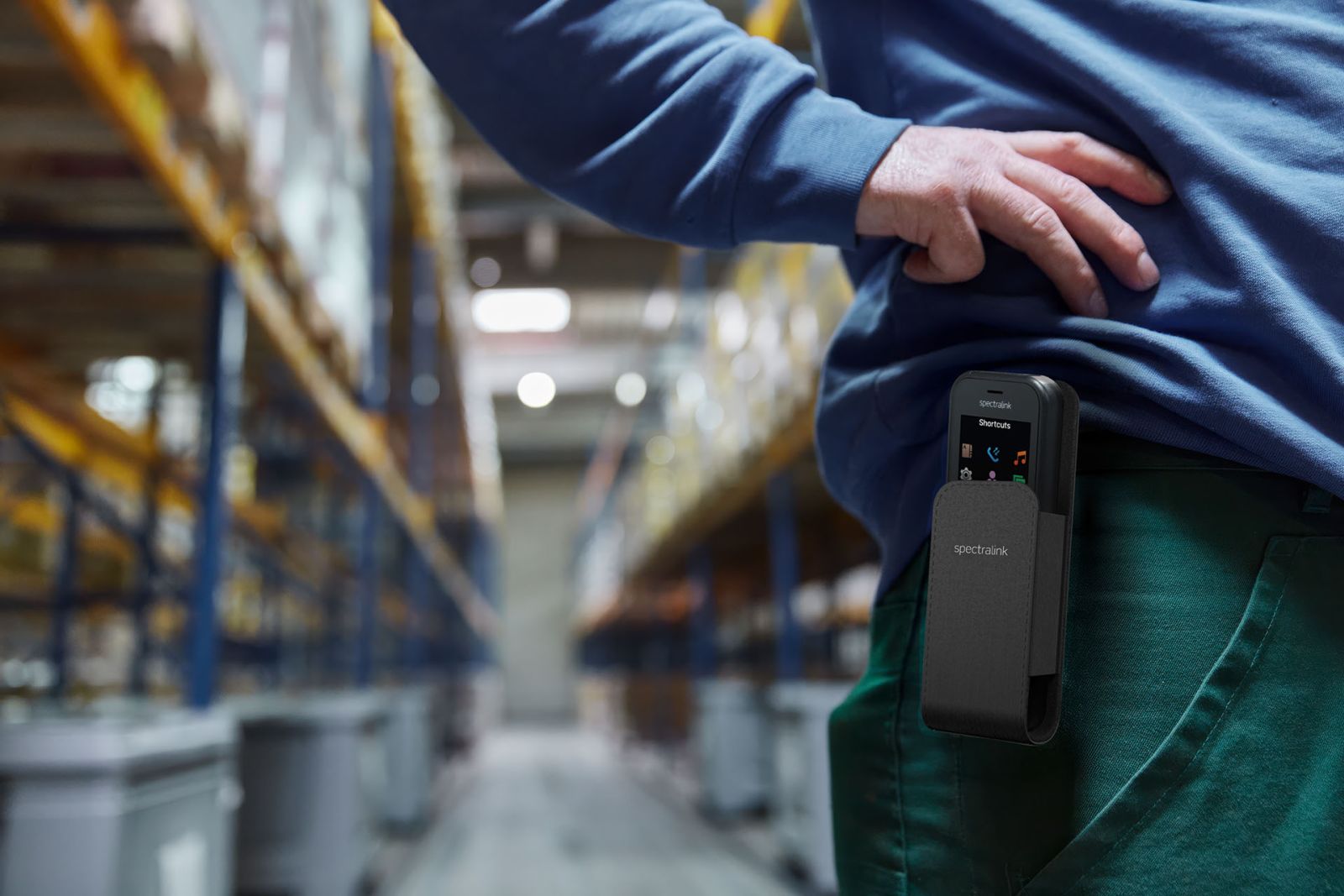 Mitarbeiter in einer Lagerhalle mit einem tragbaren mobilen Telefon in einer Gürteltasche
